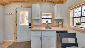A kitchen with white cabinets, a wooden ceiling, and a window with a view of trees. - Close to Trails: Studio w/ Water Views (Wurtsboro)