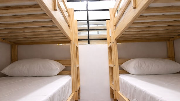 Une chambre avec un lit superposé, une lucarne, du linge de lit blanc et des poutres en bois.