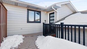 A residential building with a covered porch, a black railing, and a window.