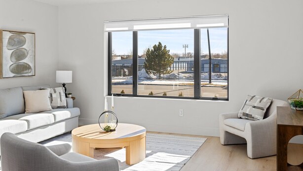 A modern living room with a large window, a sofa, a coffee table, and a side table.