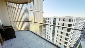 Ein Balkon mit Fliesenboden, einem Metallgeländer und Blick auf moderne Gebäude.