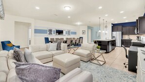 A modern living room with a sectional sofa, a glass coffee table, and a dining area with chairs and a table.