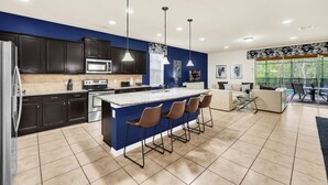 A modern kitchen with dark cabinets, a central island with bar stools, and pendant lighting.
