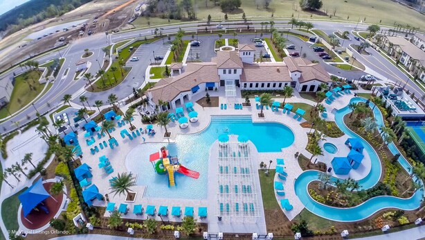 An aerial view of a hotel with a large swimming pool, multiple water slides, and a parking lot.
