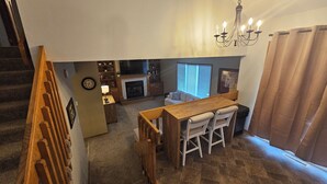 A compact living space with a dining area, a fireplace, and a staircase leading to an upper level. - Hawthorne Hideaway (West Des Moines)