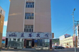 Un edificio con un letrero que dice 'XINHEI' y un número de contacto.