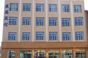 Un edificio de varios pisos con fachada color crema y numerosas ventanas.