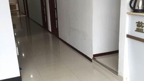 A hallway with a polished floor, a door on the left, and a wall-mounted shelf with a kettle on the right. - Fenglin Blueberry Hotel (Fenglin County)