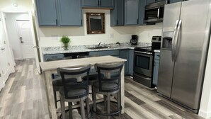 Una cocina moderna con gabinetes azul oscuro, un refrigerador de acero inoxidable y una encimera de mármol.
