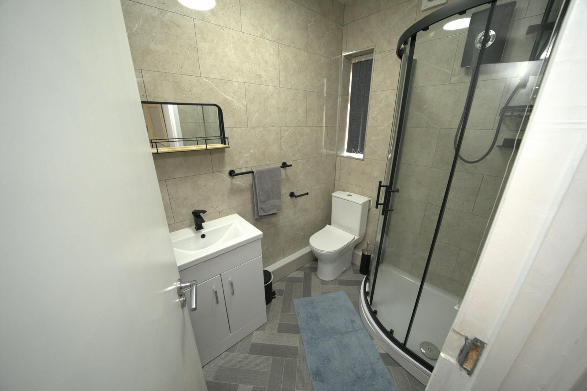 Ein modernes Badezimmer mit einer begehbaren Glasdusche, einem weißen Waschbecken und einer Toilette.