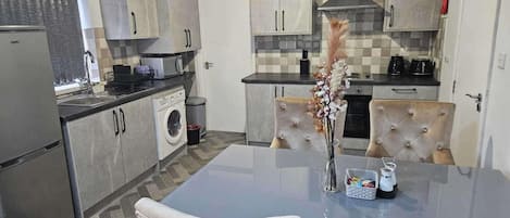 A modern kitchen with a dining area, featuring a central island, built-in appliances, and a checkered backsplash.