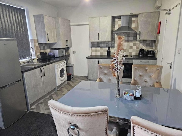A modern kitchen with a dining area, featuring a central island, built-in appliances, and a checkered backsplash.