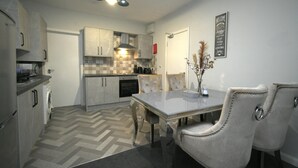 A modern kitchen with a herringbone floor, a dining table with chairs, and pendant lighting.