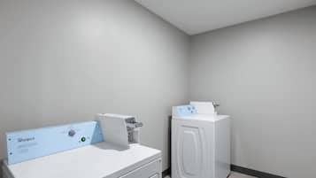 Un lavadero con lavadora y secadora de carga frontal, un panel de control y una secadora montada en la pared.