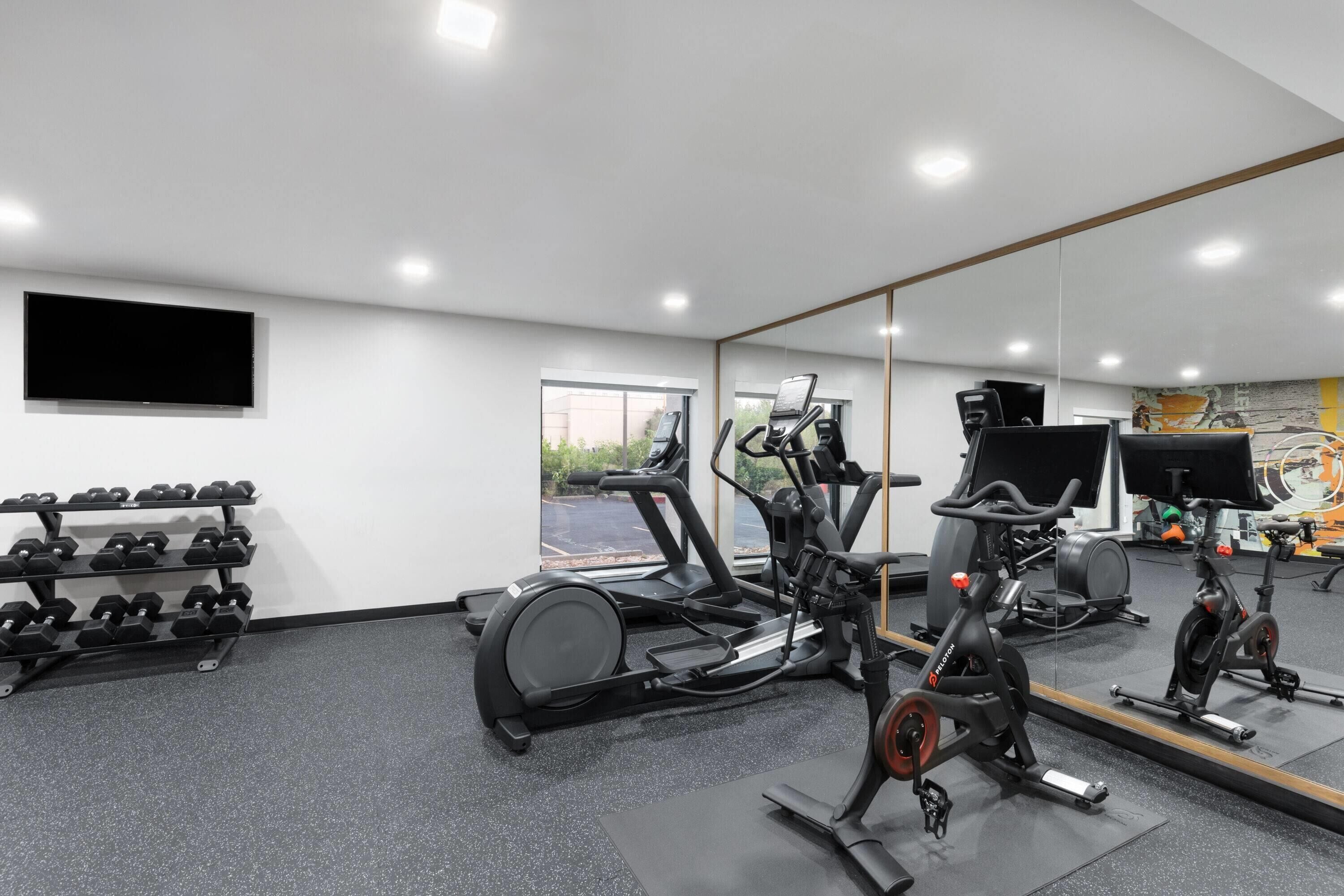 Une salle de sport équipée de matériel d’exercice, d’un téléviseur et d’un miroir.