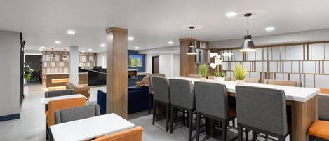 A modern dining area with wooden paneling, white tables, and grey upholstered chairs.