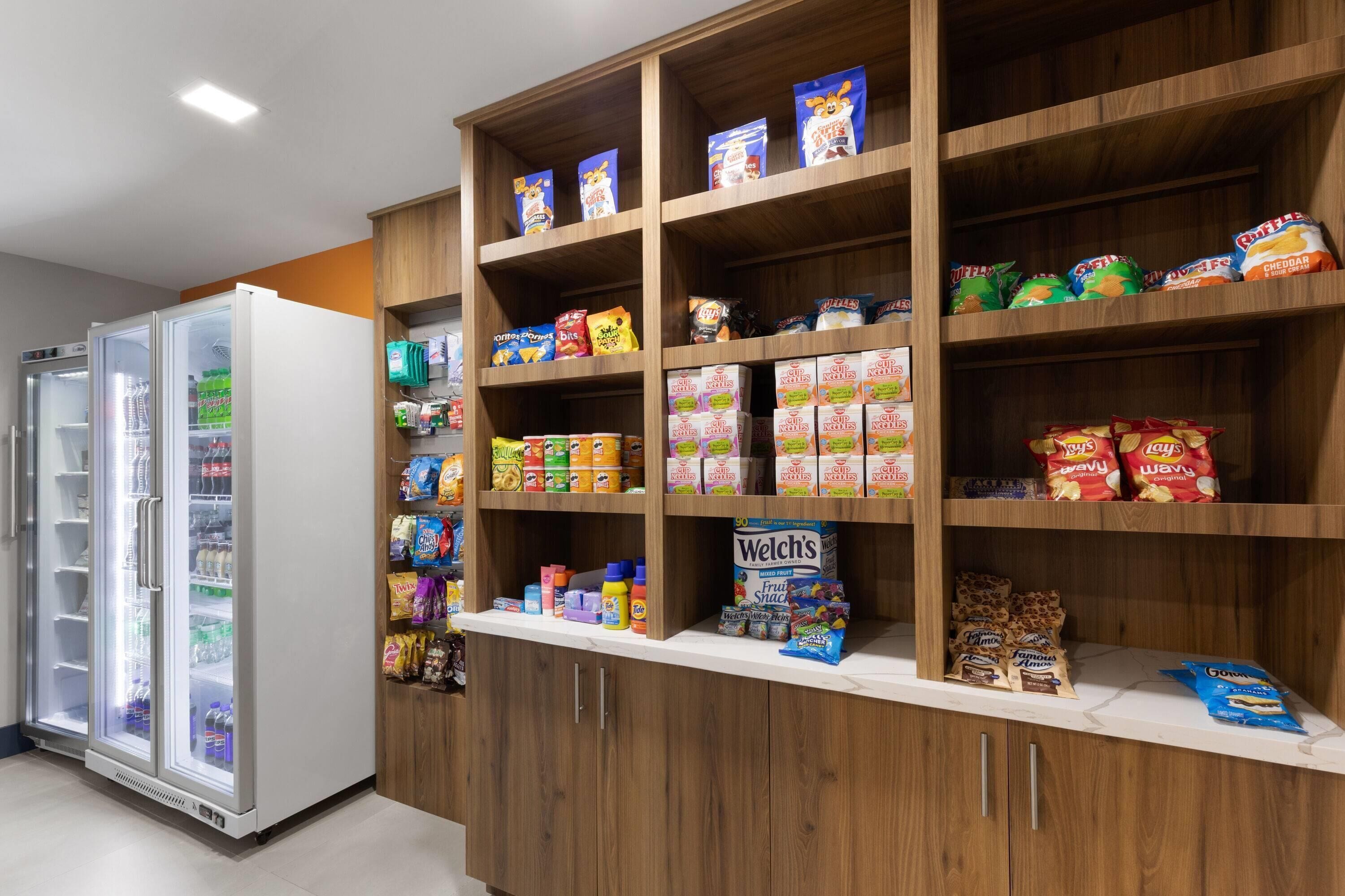 Un espace dédié à la présentation de collations et de boissons, avec une variété de produits emballés, des boissons et un compartiment réfrigéré.