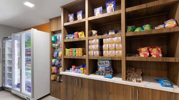 Un espace dédié à la présentation de collations et de boissons, avec une variété de produits emballés, des boissons et un compartiment réfrigéré.
