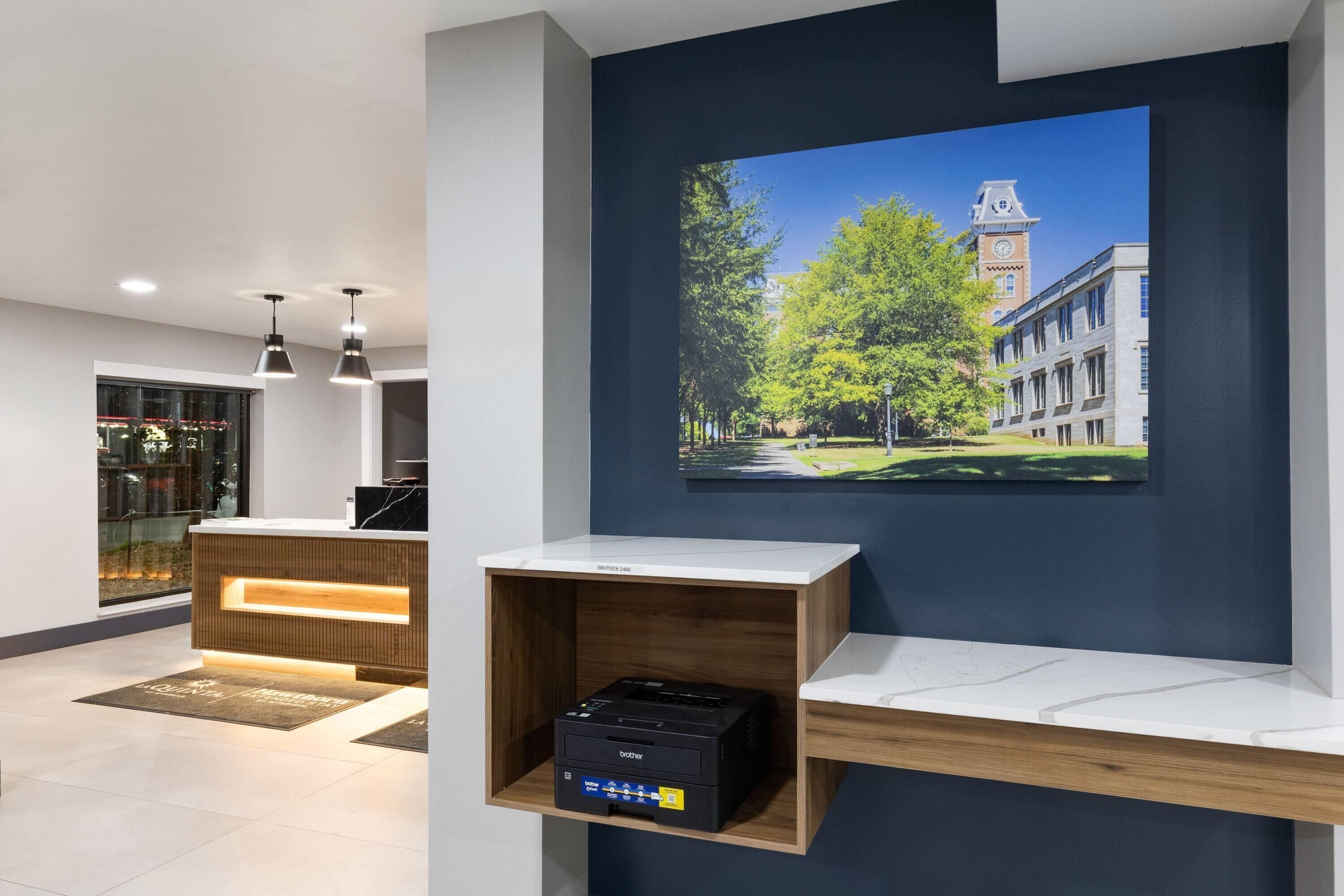 A reception desk with a Brother printer, a framed photo on the wall, and pendant lighting.