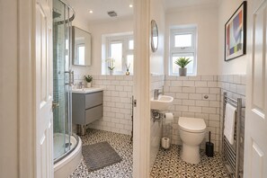A bathroom with a shower, sink, toilet, and a mirror.