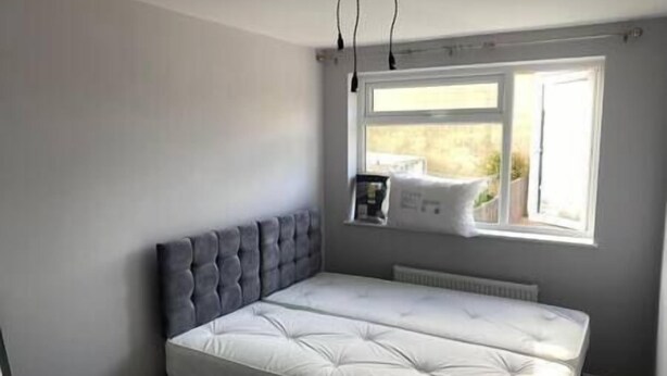 A bedroom with a bed, a window, and a radiator. - Spacious & Cozy 3 Bedroom Home in Bexleyheath (Bexleyheath)