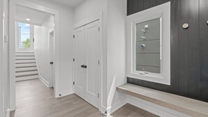 A modern hallway with white doors, a dark accent wall, and a window with blinds.