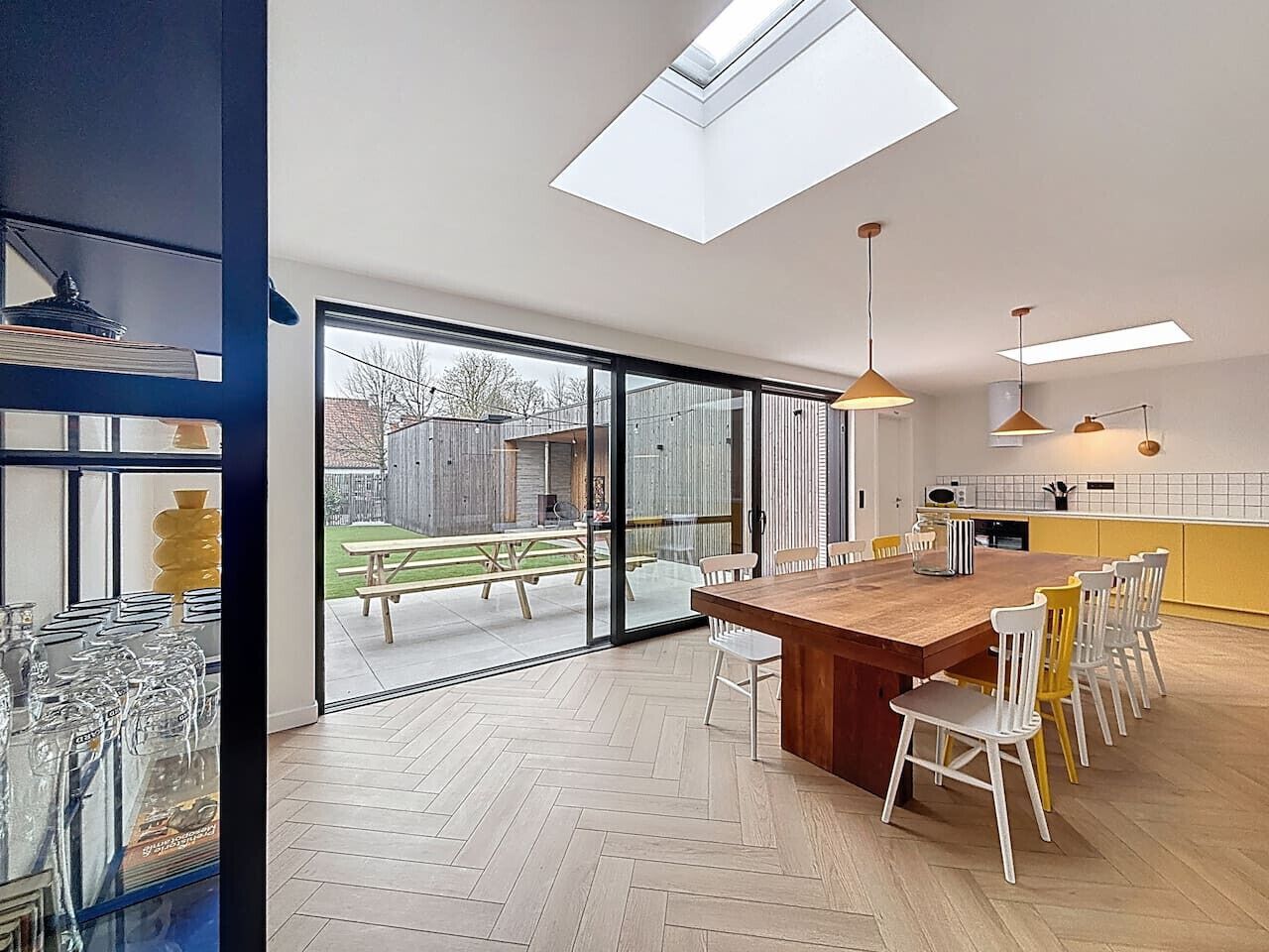 Een moderne keuken met een groot eiland, grote ramen en uitzicht op de achtertuin.