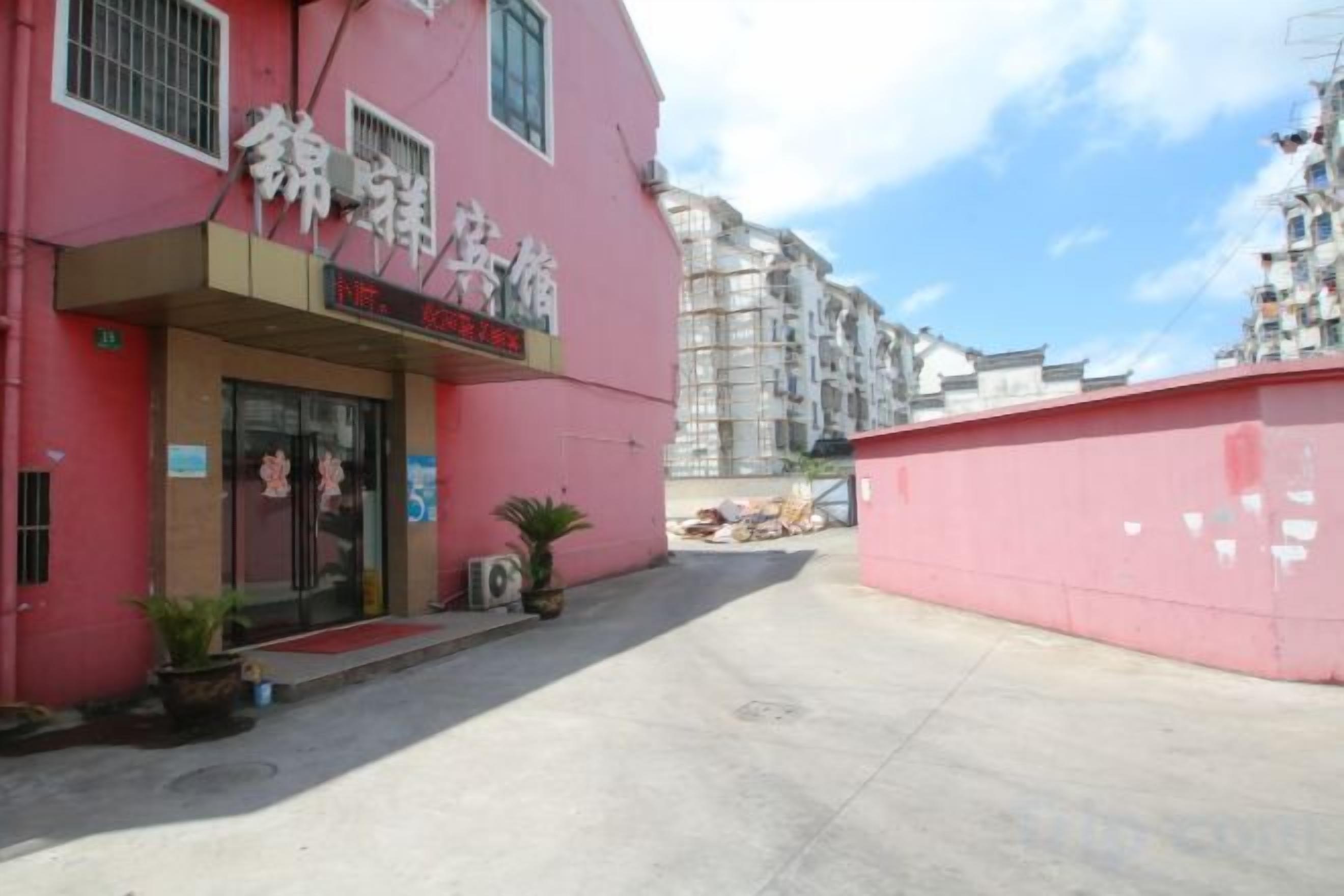 A pink building with a storefront, a clear sky, and a red awning.