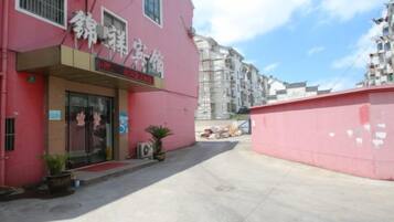 A pink building with a storefront, a clear sky, and a red awning.
