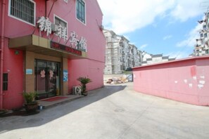 Un edificio rosa con escaparate, cielo despejado y toldo rojo.