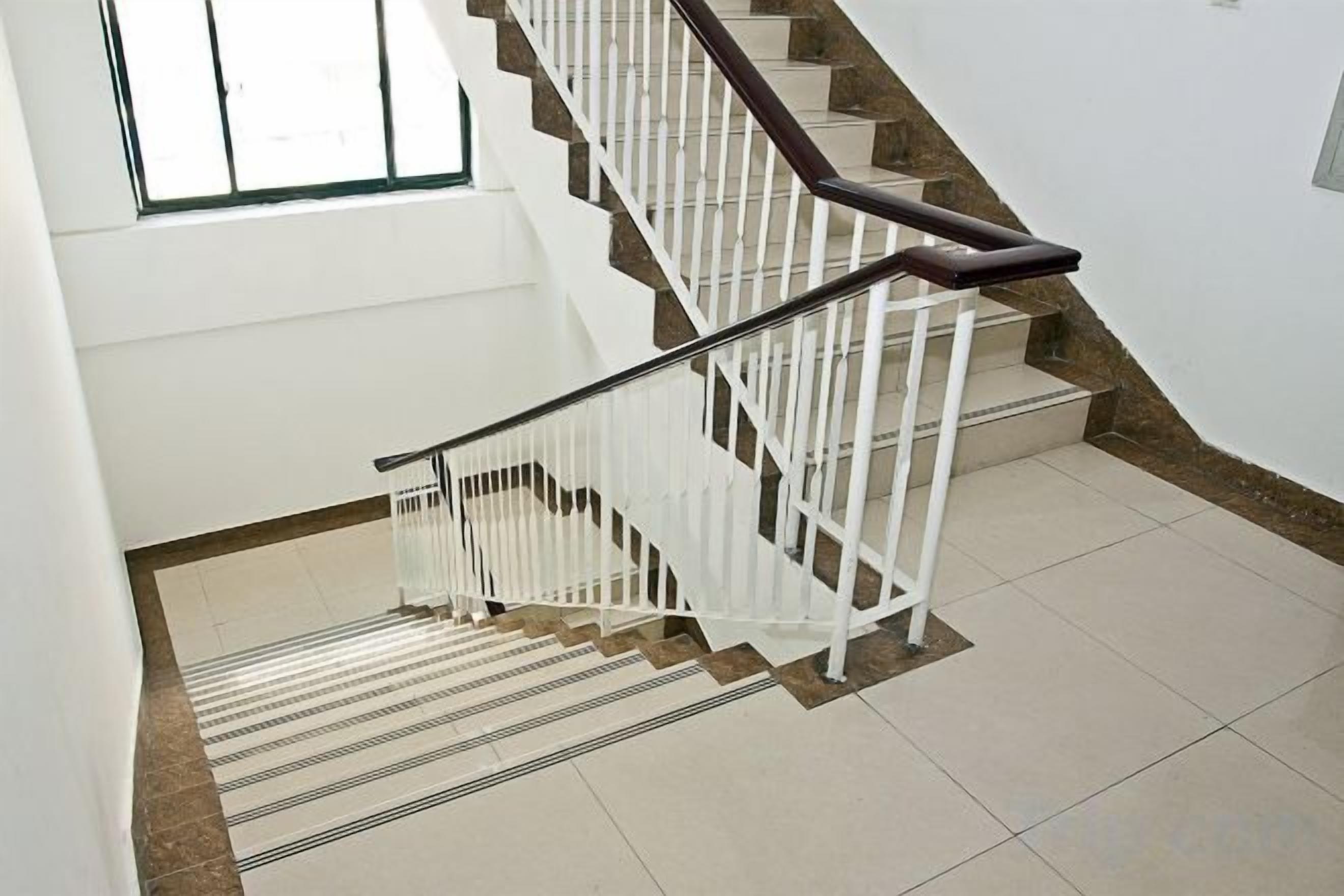 A staircase with white railings and a handrail, leading to an upper floor.