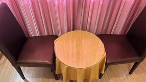 A round table with a yellow tablecloth, two brown leather chairs, and a pink curtain backdrop. - Shanghai Jinxiang Hotel (Zhujiajiao Ancient Town) (Shanghai)