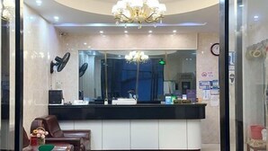 A reception area with a black counter, a chandelier, a large mirror, and leather seating. - Shanghai Jinxiang Hotel (Zhujiajiao Ancient Town) (Shanghai)