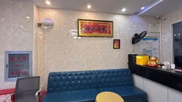 A reception area with a blue sofa, a round table, a laptop on the sofa, a framed picture on the wall, and a counter with various items.