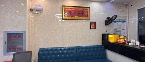 A reception area with a blue sofa, a round table, a laptop on the sofa, a framed picture on the wall, and a counter with various items.