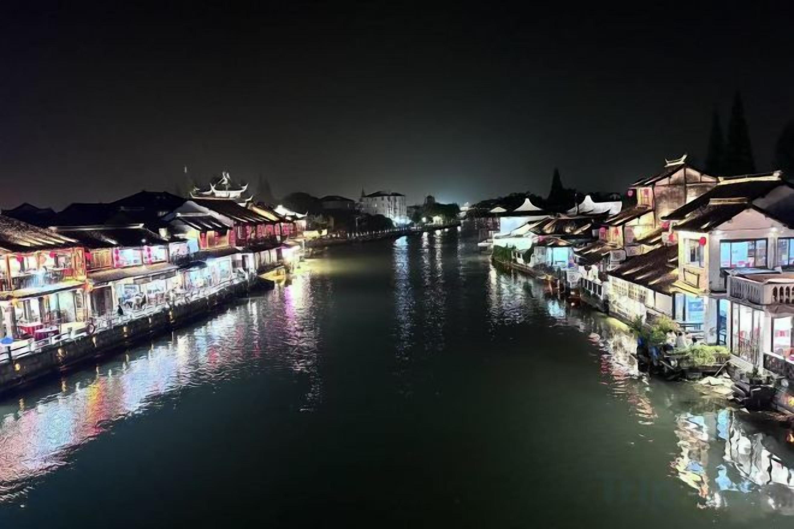 Um rio com edifícios em ambas as margens, alguns com luzes refletindo na água.