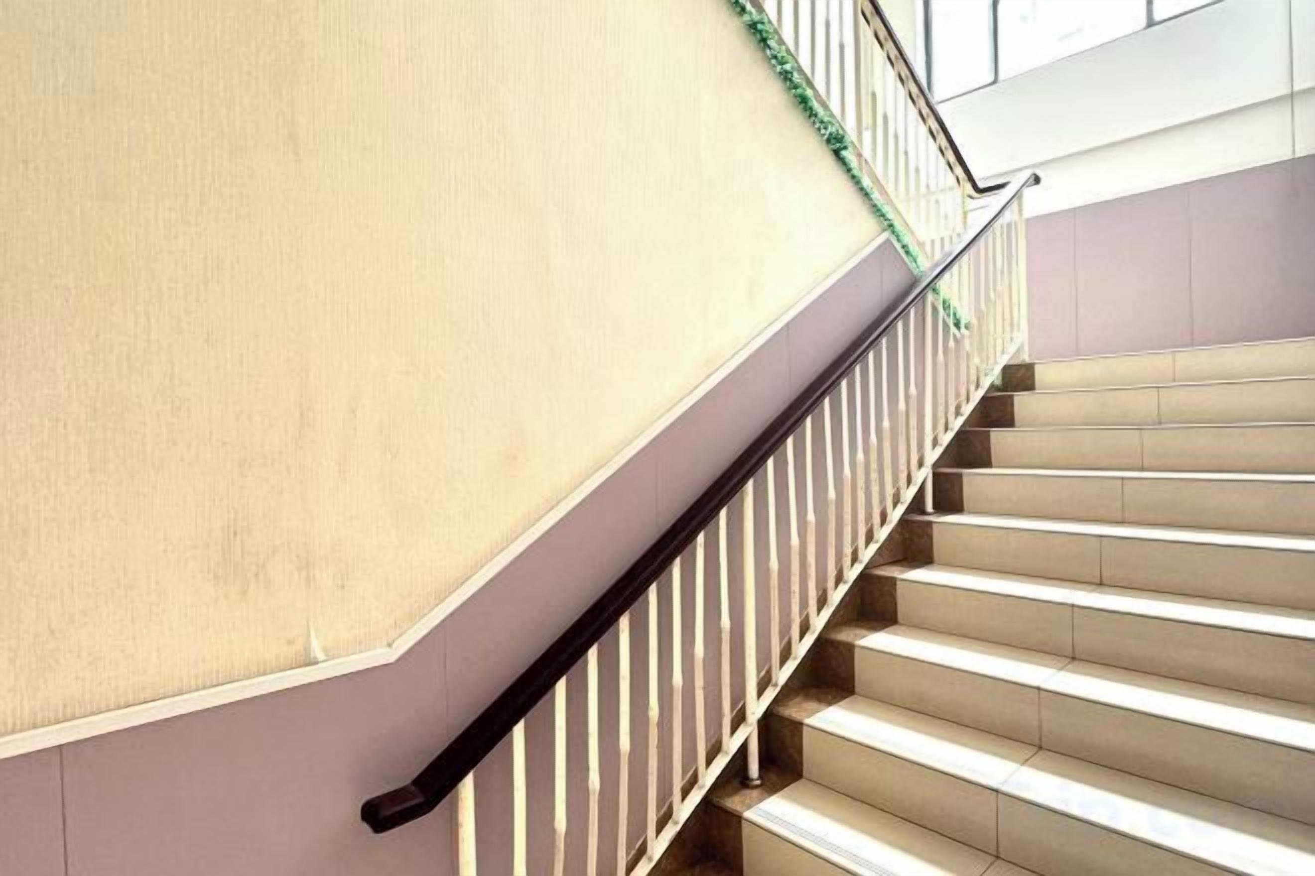A staircase with a handrail and a wall with a textured surface.