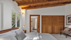 A bedroom with a large bed, wooden ceiling beams, a wardrobe, and a chair. - Stunning Neighborhood Home Walkable to Downtown Mill Valley (Mill Valley)