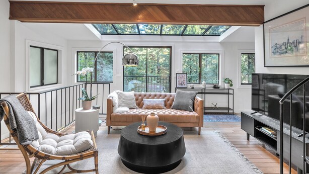 A modern living room with a high ceiling, large windows, a sofa, a chair, a coffee table, and a TV. - Stunning Neighborhood Home Walkable to Downtown Mill Valley (Mill Valley)