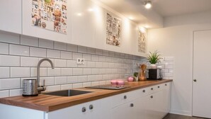 Uma cozinha moderna com armários brancos, bancada de madeira, pia de aço inoxidável e micro-ondas.