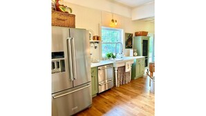 Una cocina moderna con electrodomésticos de acero inoxidable, armarios verde claro y suelo de madera.