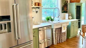 Una cocina moderna con electrodomésticos de acero inoxidable, armarios verde claro y suelo de madera.