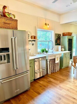 Una cocina moderna con electrodomésticos de acero inoxidable, armarios verde claro y suelo de madera.