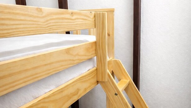 Una cama litera con estructura de madera y un colchón con almohada de diseño gris y blanco.