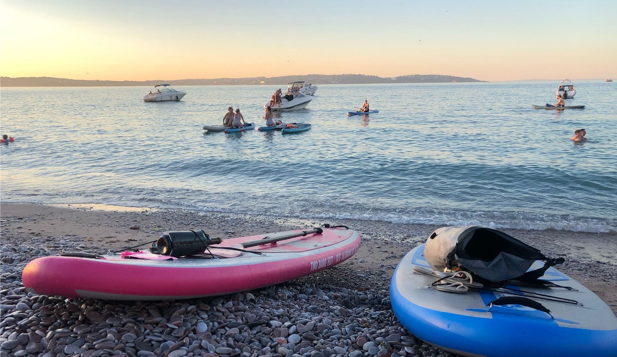 Una playa con balsas inflables y barcos en el agua.