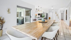 Una cocina moderna con una isla grande de madera, sillas blancas y una mesa de comedor.