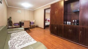 Une pièce comprenant un canapé, une table à manger avec des chaises, une armoire et un lit à l’arrière-plan.