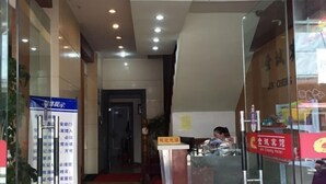Un espace d’accueil d’hôtel comprenant un comptoir de réception, un panneau d’information bleu et un panneau rouge indiquant le nom de l’hôtel.