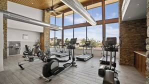 A gym with various exercise equipment, large windows, and a stone wall. - Resort-Style Gated, Pool Gym Near Downtown Phoenix & Chase Field Hiking Mountain (Phoenix)