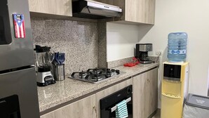 A modern kitchen with granite countertops, a built-in stove, a dishwasher, and a water dispenser. - OCEAN DRIVE, Apartamento frente al mar (Cartagena)
